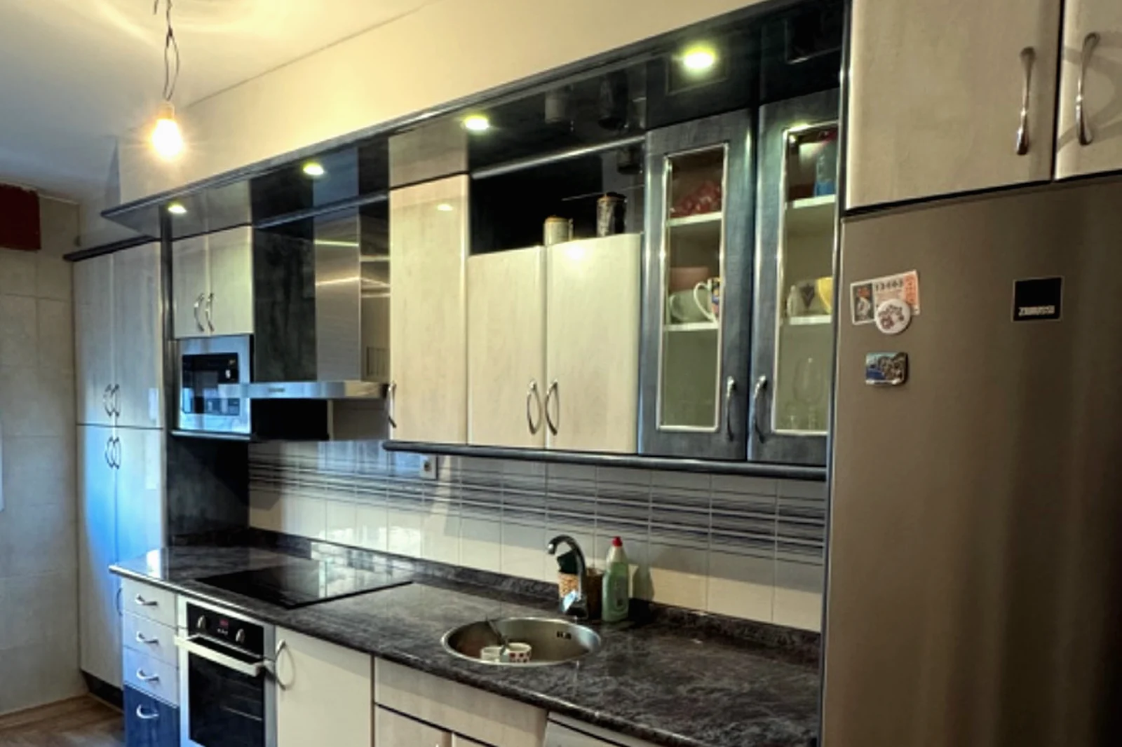 Cocina larga con frentes revestidos y electrodomésticos integrados