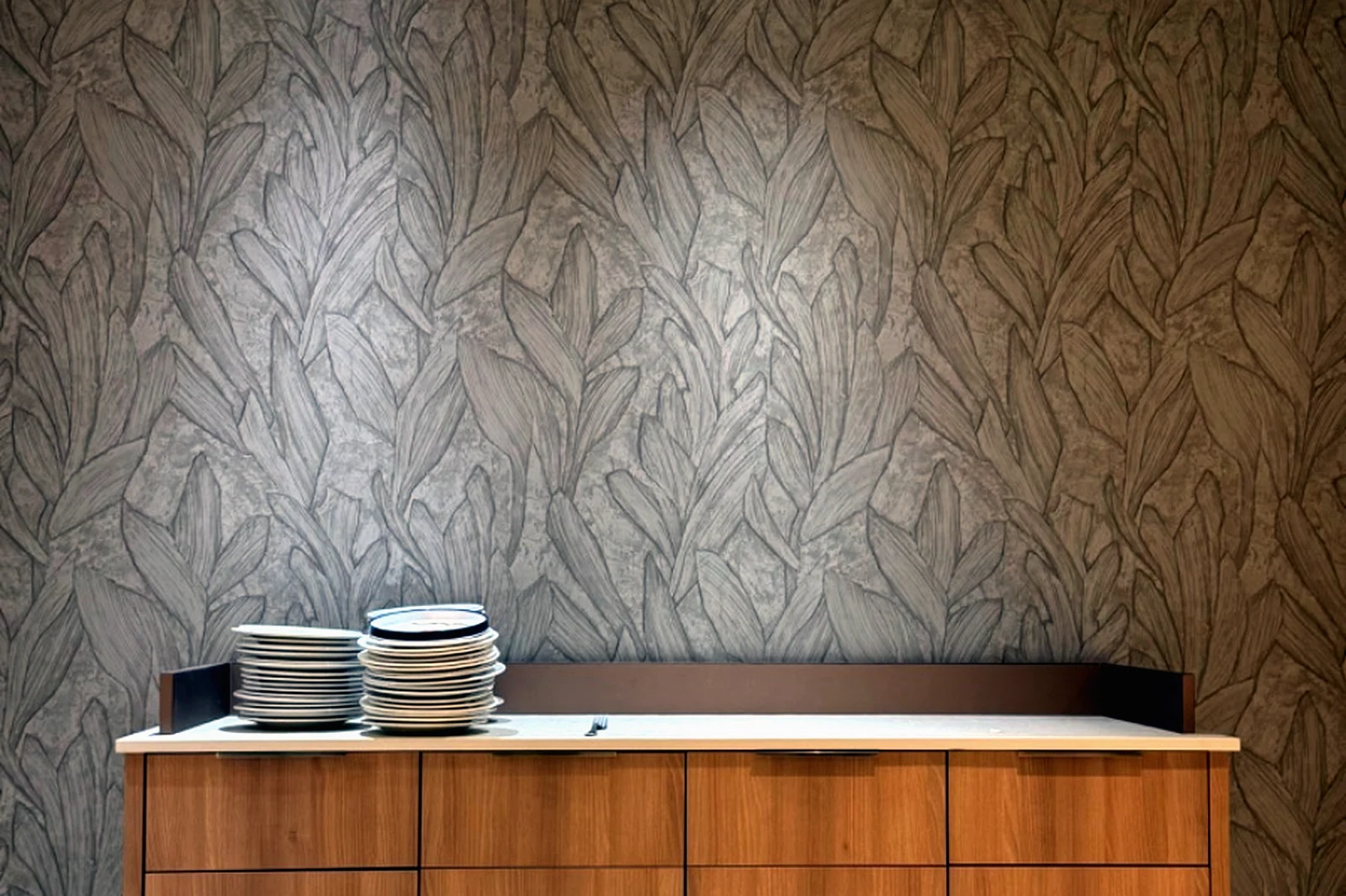 Pared con papel pintado de dibujo vegetal y mueble de madera